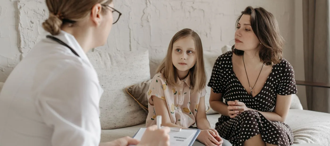 Rooted Family Chiropractic — a chiropractor talking with a mother and her daughter during a calm, unhurried visit