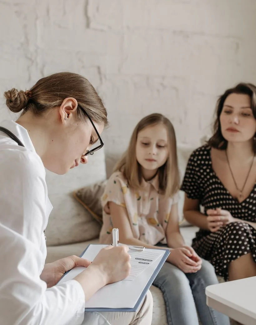 Rooted Family Chiropractic — a chiropractor listening and taking notes with a mother and child before care begins