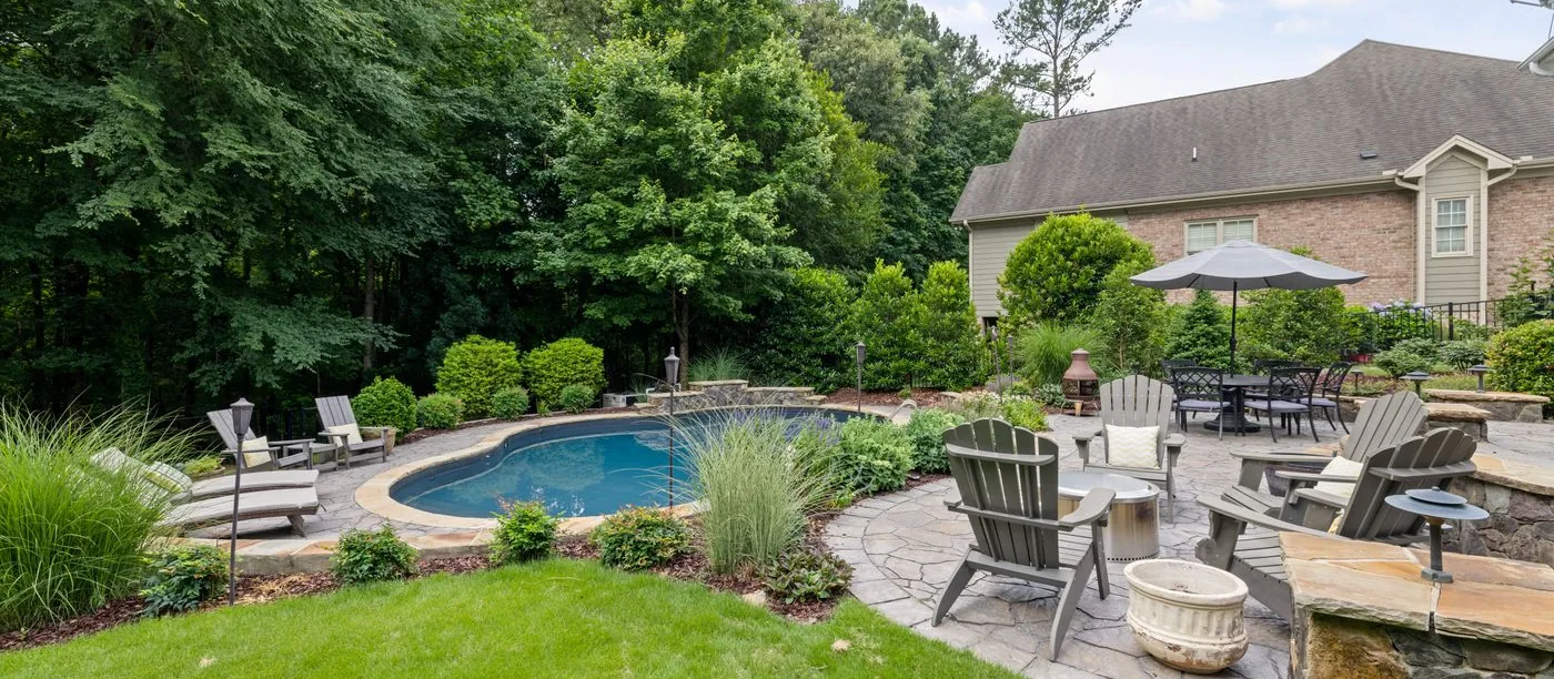 StoneForge Outdoor Living โ a finished flagstone patio with seating and fire feature in a landscaped backyard