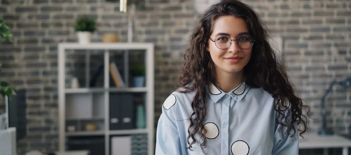 Confident creator in glasses standing in a bright, modern studio office