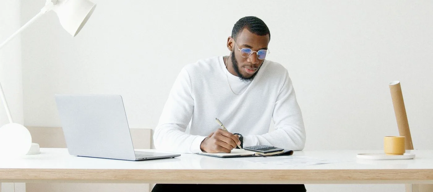 Creator working at a clean, minimalist desk with a laptop and notebook