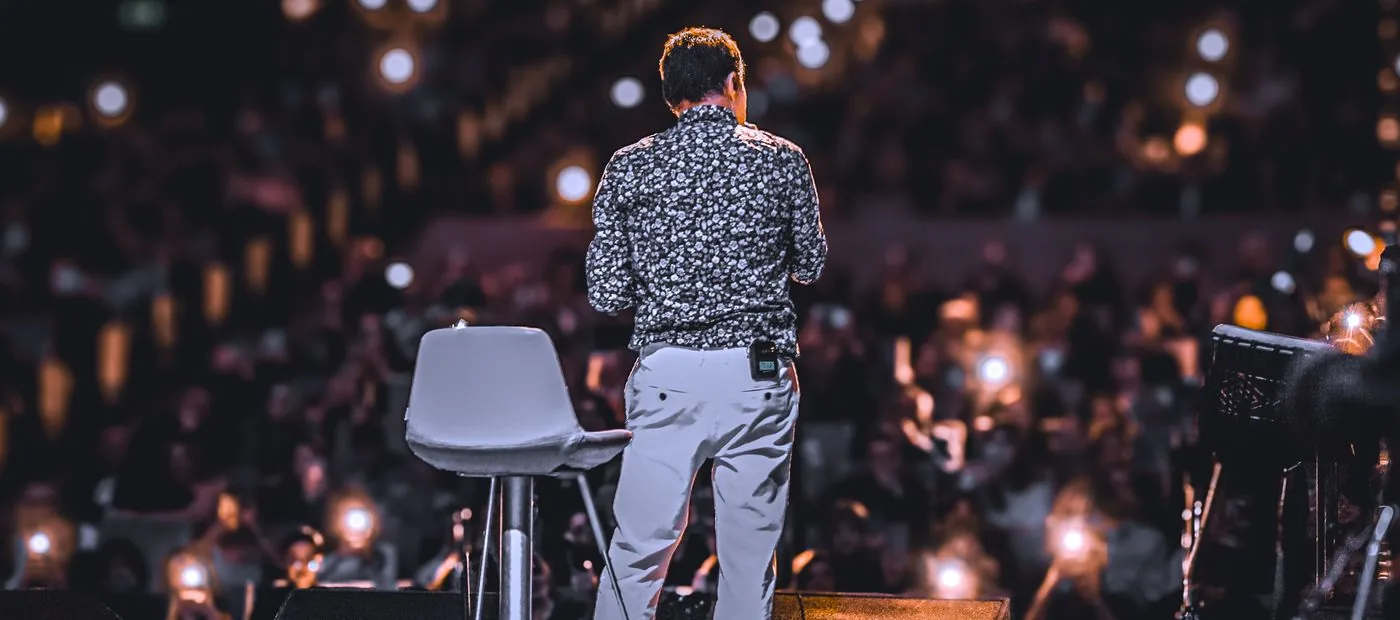 Speaker addressing a large audience under stage lights